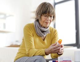 A woman on a couch looking at a prescription pill bottle