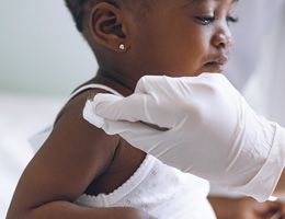 A healthcare worker swabs a child's shoulder.