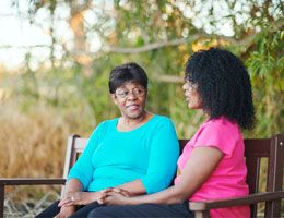 Two Black women sit on a bench.