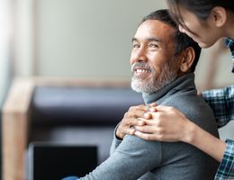 A woman puts her hand comfortingly on a man's shoulder