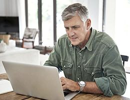 A man works on a laptop at home.