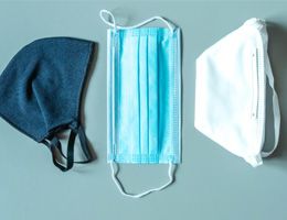 Two cloth face masks and a surgical mask lying side by side.