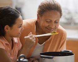 A grandmother and granddaughter cooking in a kitchen.