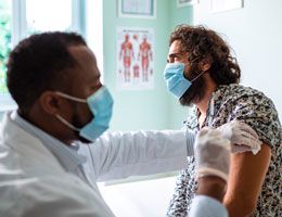 A healthcare provider prepares to give a man a shot.