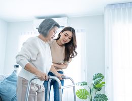 A young woman helps an holder woman using a walker