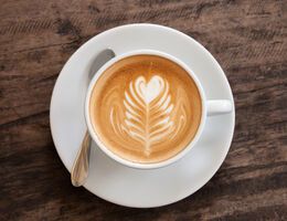 Milk in a latte forming a leaf shape with a heart on top.