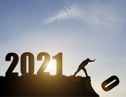 Silhouetted "2021" on a hillside with someone pushing "0" over the edge.