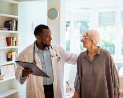 Doctor smiling and placing hand on patients shoulder.