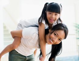 A mom giving her daughter a piggyback ride.