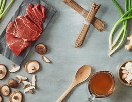 Lean beef top sirloin surrounded by green onions, noodles, and mushrooms.