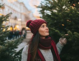 A young woman shopping for a Christmas tree alone.