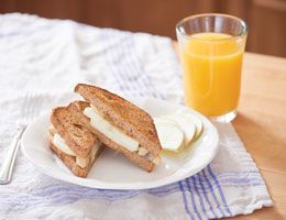 French toast fritters with bananas, sliced apples and a glass of orange juice.