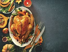 A cooked turkey on a serving plate surrounded by vegetables.