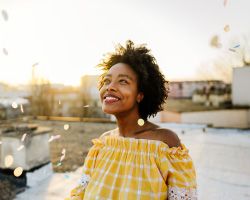 A smiling woman stands on a rooftop