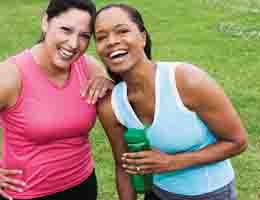 Two smiling women outdoors in tank tops.