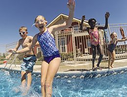 A group of kids jumping into a swimming pool.