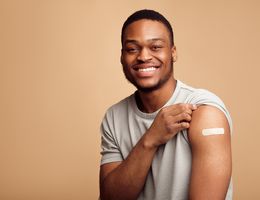 A man holds up his sleeve to show his vaccine bandage