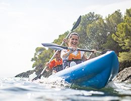 Two people laugh while paddling in a kayak.