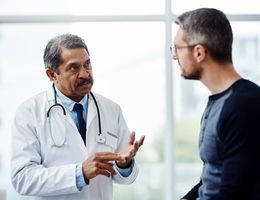 A doctor gestures as he talks to a patient