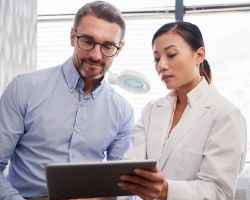 A man and his female doctor look at a tablet together.