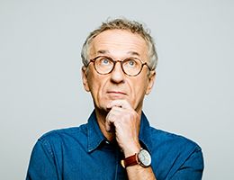 A man looks up, thinking, with a hand on his chin.