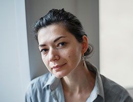 A woman looks thoughtfully at the camera.