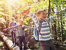 3 kids walking on a log while hiking.