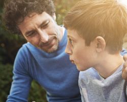 A man sits with his arm around a worried boy