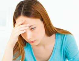 A young woman rests her hand on her forehead