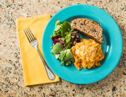 Turkey meatloaf on a blue plate with salad and macaroni.