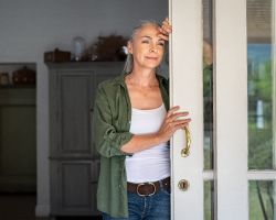  An older woman looks pensively out her sliding door