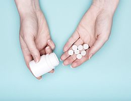 A pair of hands holding pills and a pill bottle.
