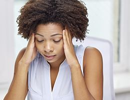 A woman in pain massages her forehead.