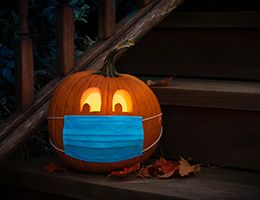 A jack-o'-lantern wearing a cloth face mask.