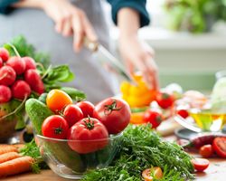 Bunches of radishes, carrots, tomatoes, cucumbers, lettuce and peppers cover a countertop.