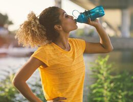 A woman drinks water from a reusable water bottle.