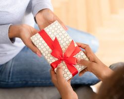 Two sets of hands exchanging a small, wrapped gift.