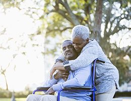 A woman embraces a man in a wheelchair.