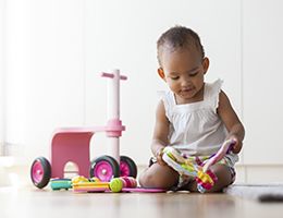 A toddler playing with toys on the floor.