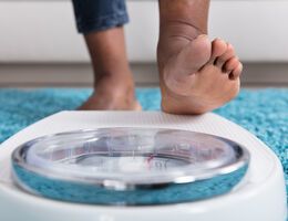 Feet stand poised to step on a bathroom scale.
