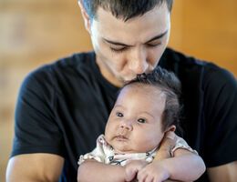  A dad kissing the top of a baby's head.