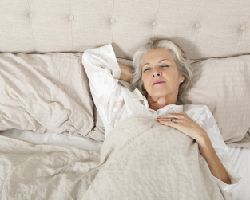 A woman sleeps in a bed.