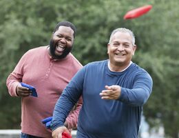  Two men playing cornhole.