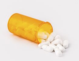 A prescription pill bottle with pills spilling out.