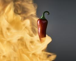 Flames burst around a chile pepper.