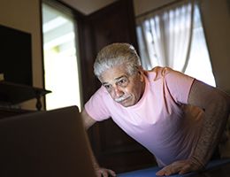 An older man is doing pushups on his living room floor.