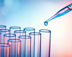 A pipette drops fluid into a row of test vials.