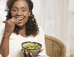 A woman eating edamame.