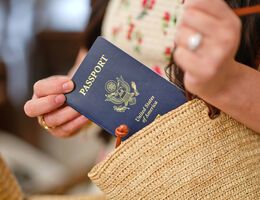 A woman's hands as she tucks a U.S. passport into her purse.