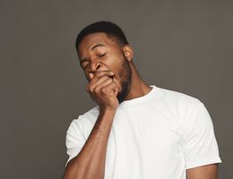 A man covers a yawn with his hand.